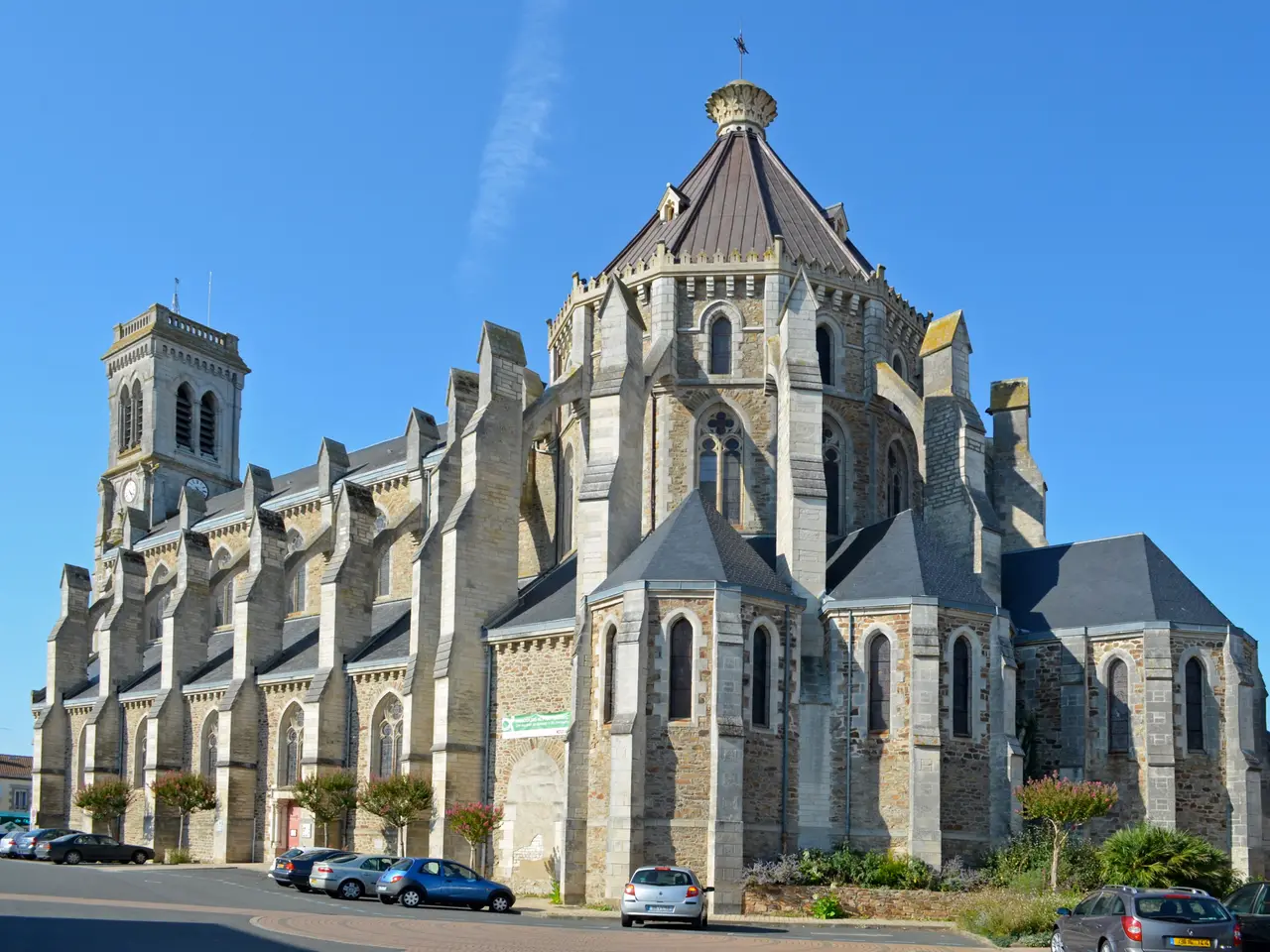 L’église Saint-Benoît d’Aizenay, vue depuis son chevet sous un ciel bleu