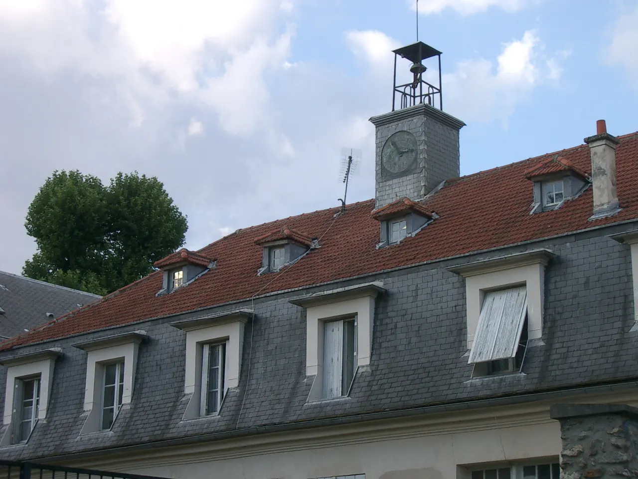 Toit de tuiles et d’ardoises de l’ancienne manufacture royale des cires d’Antony, avec ses lucarnes et son clocheton à horloge.