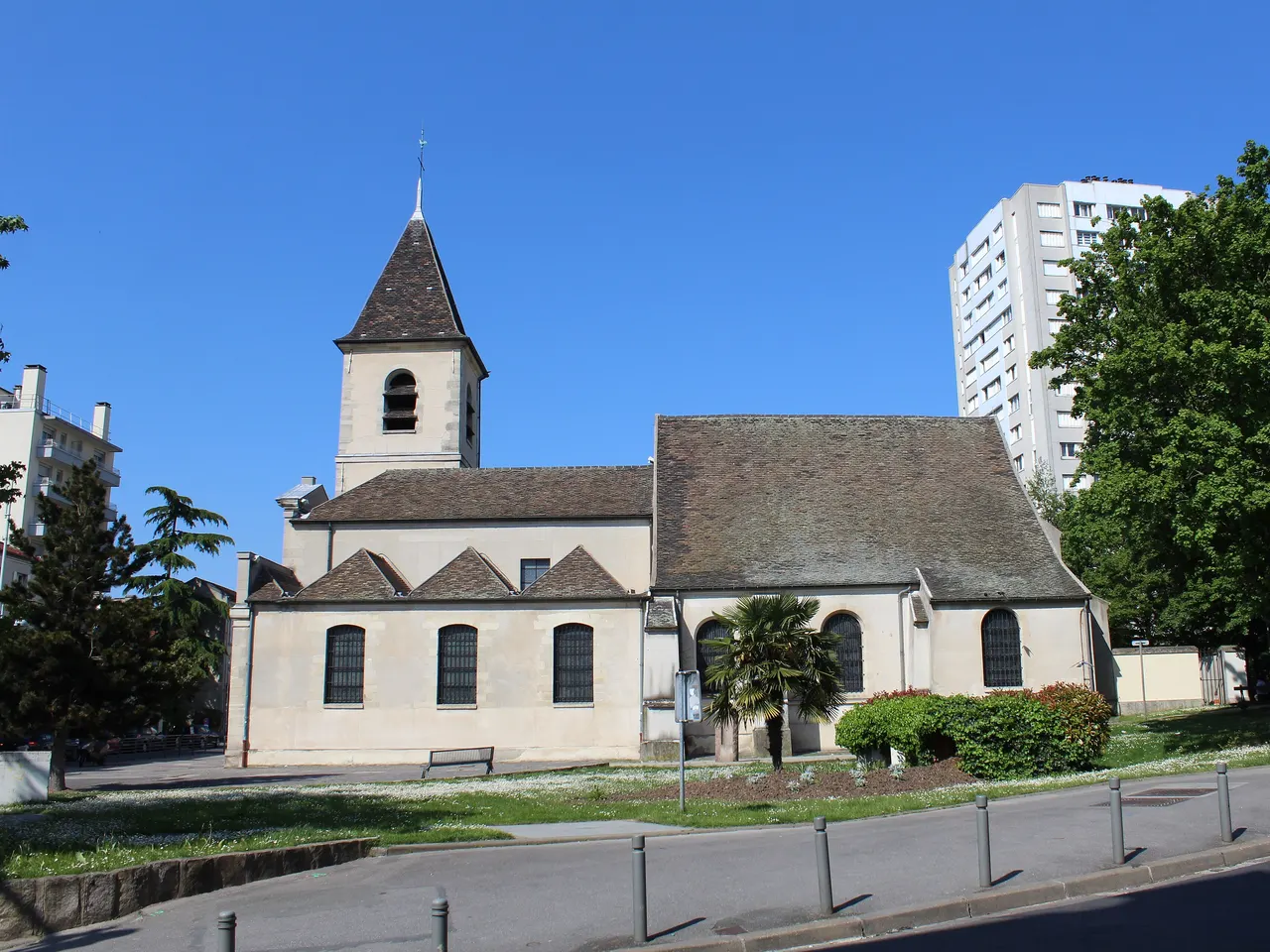 L’église Saint-Leu-Saint-Gilles de Bagnolet, son clocher pointu et ses toits de tuiles brunes, devant une tour d’habitation