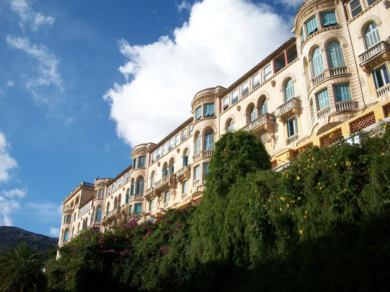 La façade Belle Époque de l’ancien hôtel Riviera Palace à Beausoleil, ses rotondes et ses balcons au-dessus d’un jardin en fleurs