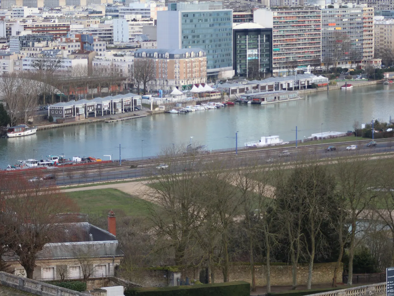 La Seine et les quais de Boulogne-Billancourt, avec péniches et immeubles de bureaux, vus depuis les hauteurs du parc de Saint-Cloud.
