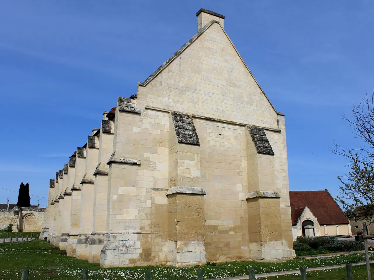 Un long bâtiment en pierre claire à contreforts et haut pignon, au domaine de la Baronnie de Bretteville-sur-Odon