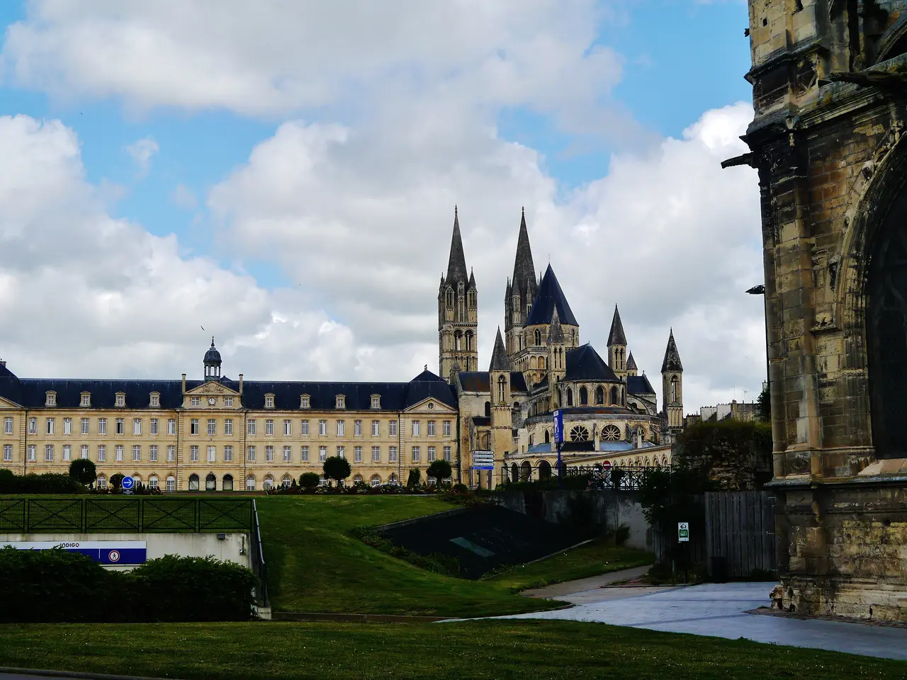 Les bâtiments de l’abbaye aux Hommes, qui abritent l’hôtel de ville de Caen, et les flèches de l’abbatiale Saint-Étienne derrière une pelouse