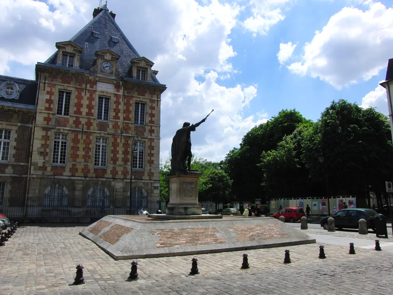 Statue d’Henri IV sur la place pavée Arthur-Dussault à Charenton-le-Pont, devant un bâtiment de brique et de pierre à horloge