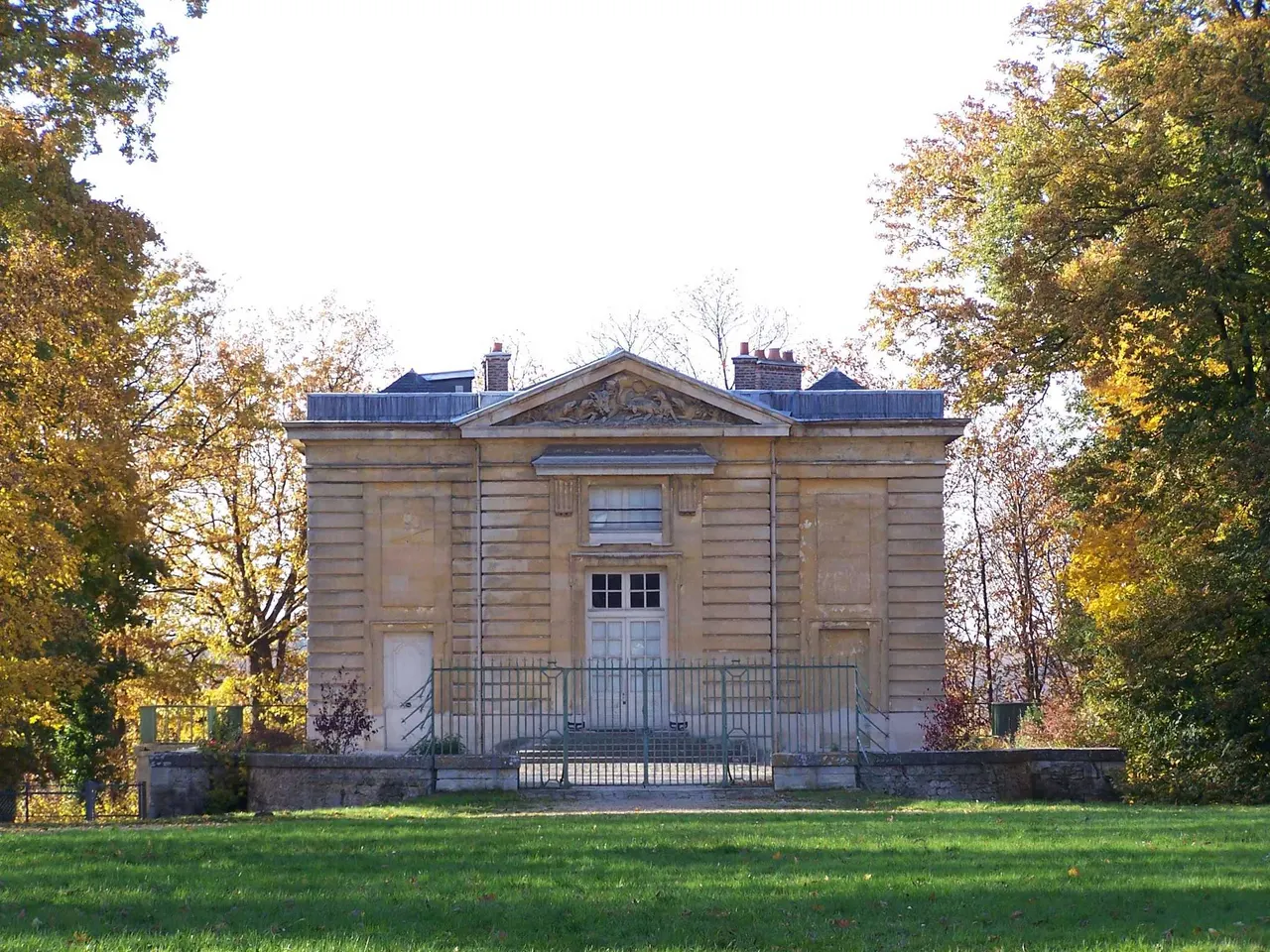 Le pavillon du Butard, pavillon de chasse classique au fronton sculpté, entouré d’arbres aux couleurs d’automne