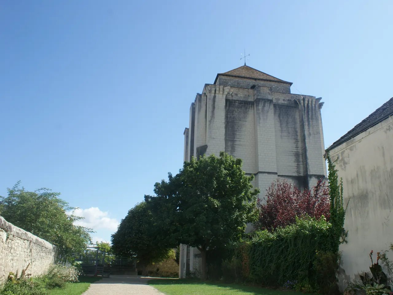 Le donjon de La Roche-Posay derrière un jardin arboré, sous un ciel bleu