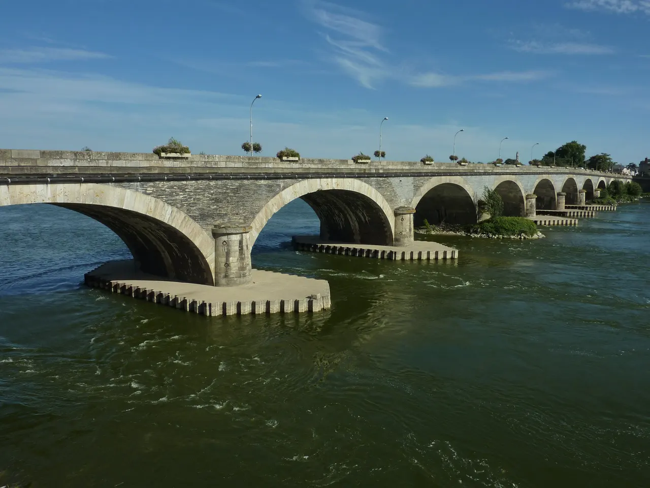 Le pont Dumnacus aux Ponts-de-Cé, longue suite d’arches de pierre posées sur la Loire, par une journée ensoleillée.