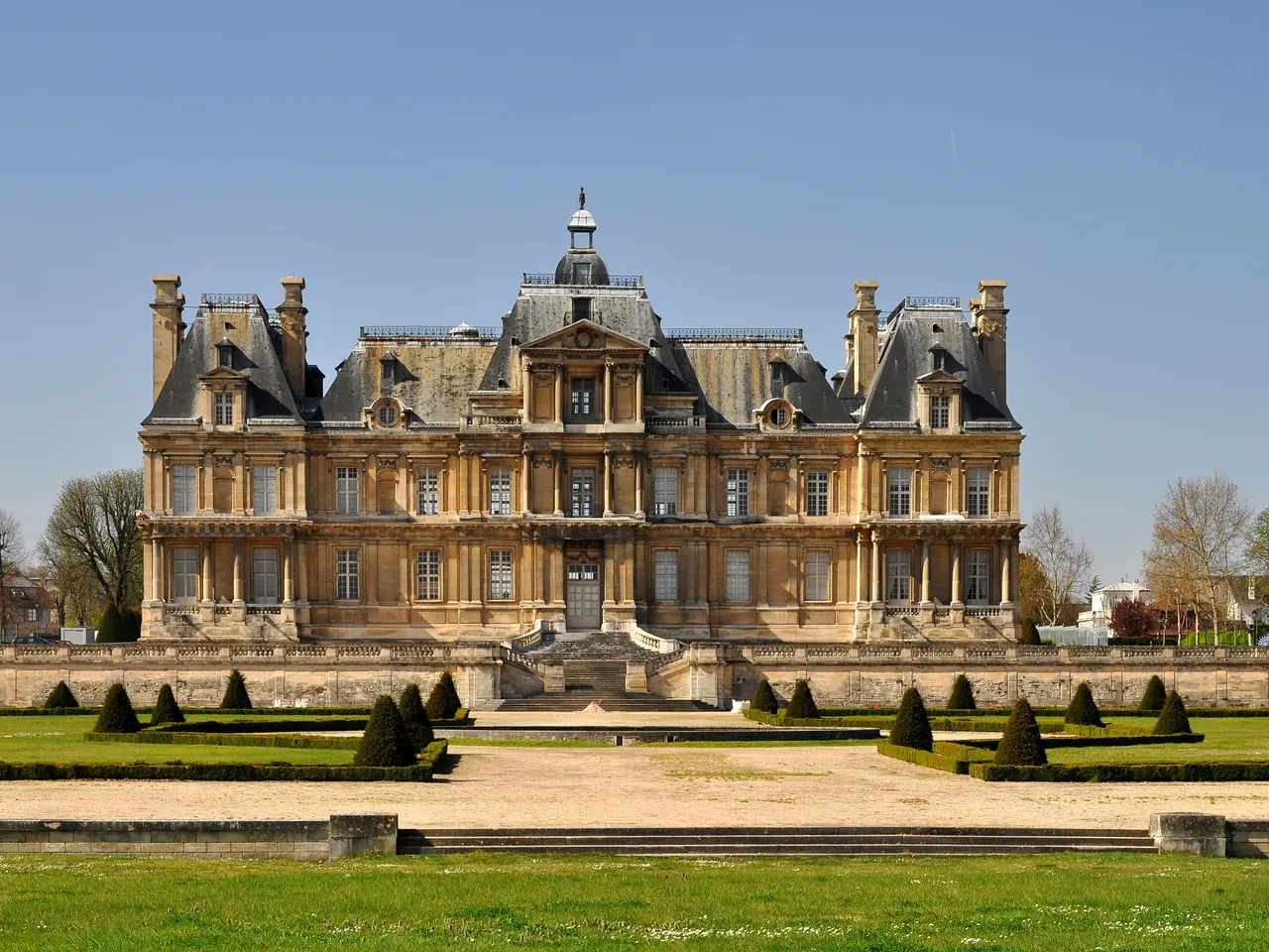 La façade du château de Maisons-Laffitte, ses hauts toits d’ardoise et ses cheminées, au-dessus du jardin à la française et de ses ifs taillés.