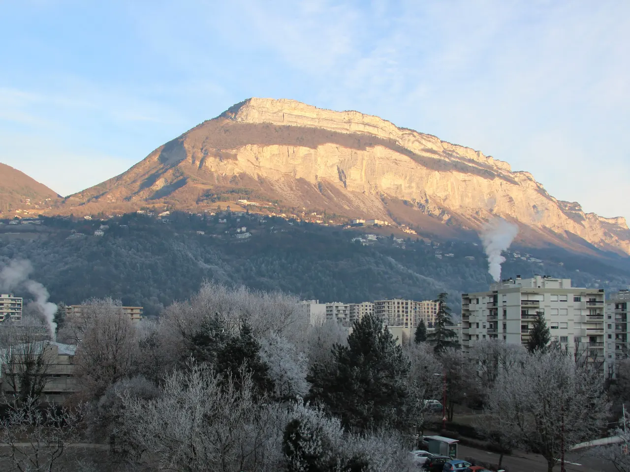 La falaise du Saint-Eynard éclairée par le soleil au-dessus des immeubles de Meylan et d’arbres couverts de givre.