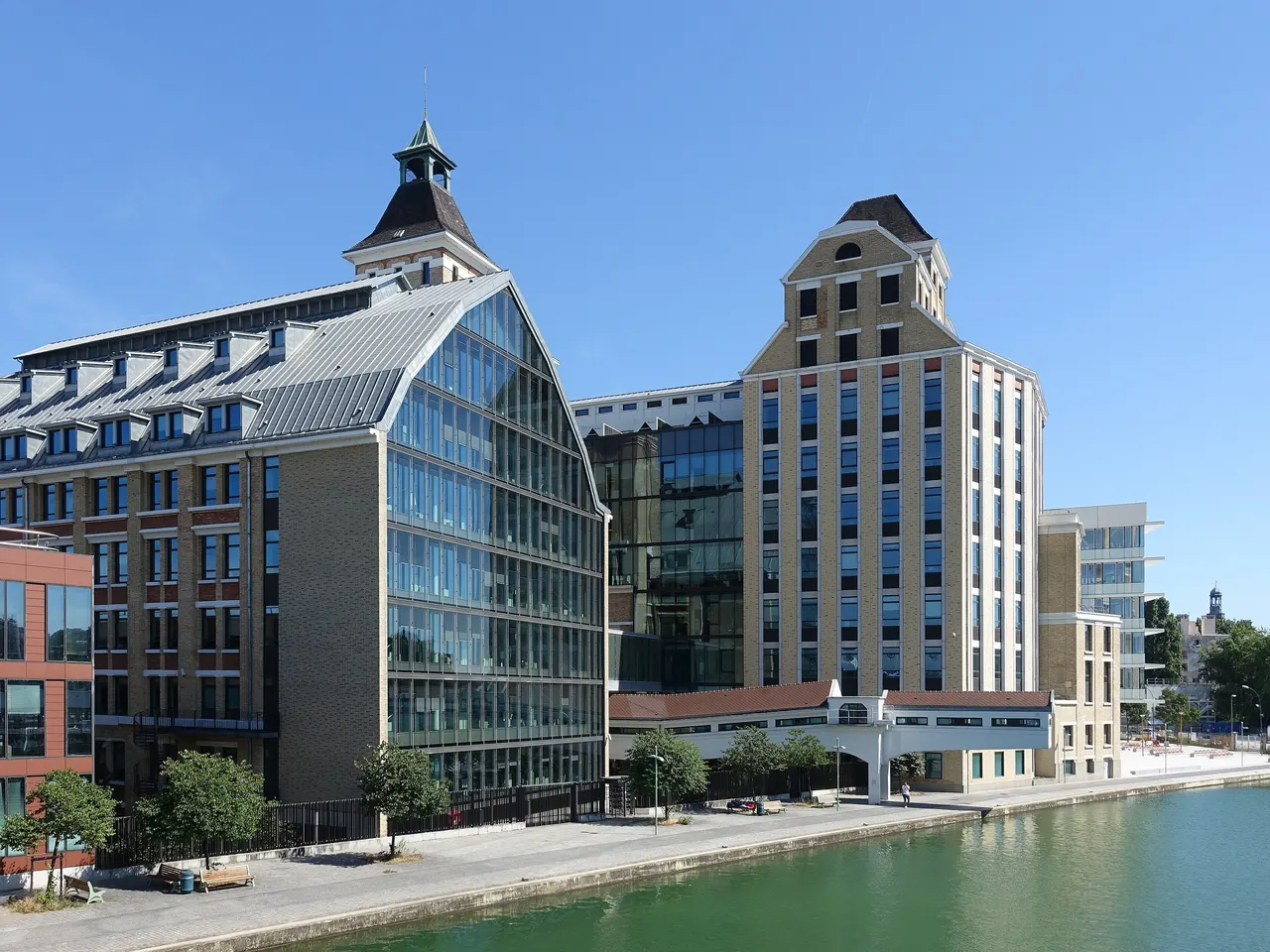 Les Grands Moulins de Pantin au bord du canal de l’Ourcq, leurs tours de brique claire coiffées de toits pointus et leur pignon vitré