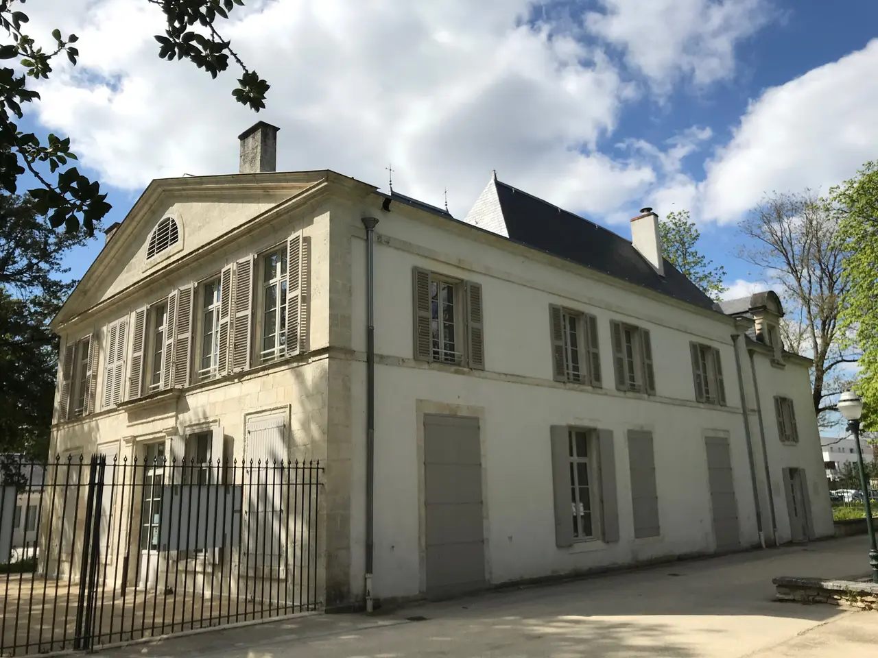 Le château de Coureilles à Périgny, aux volets gris, derrière sa grille sous un ciel nuageux