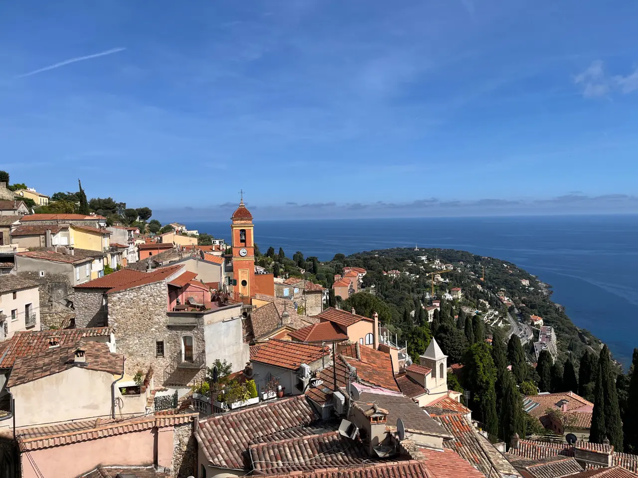 Les toits de tuiles du vieux village de Roquebrune et le clocher de son église, avec le cap Martin et la mer en arrière-plan
