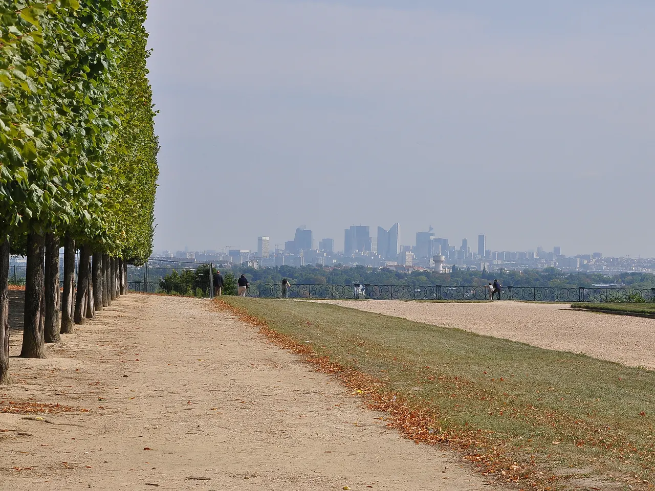 La Grande Terrasse de Saint-Germain-en-Laye, allée de sable bordée d’arbres taillés en rideau, avec au loin les tours de La Défense