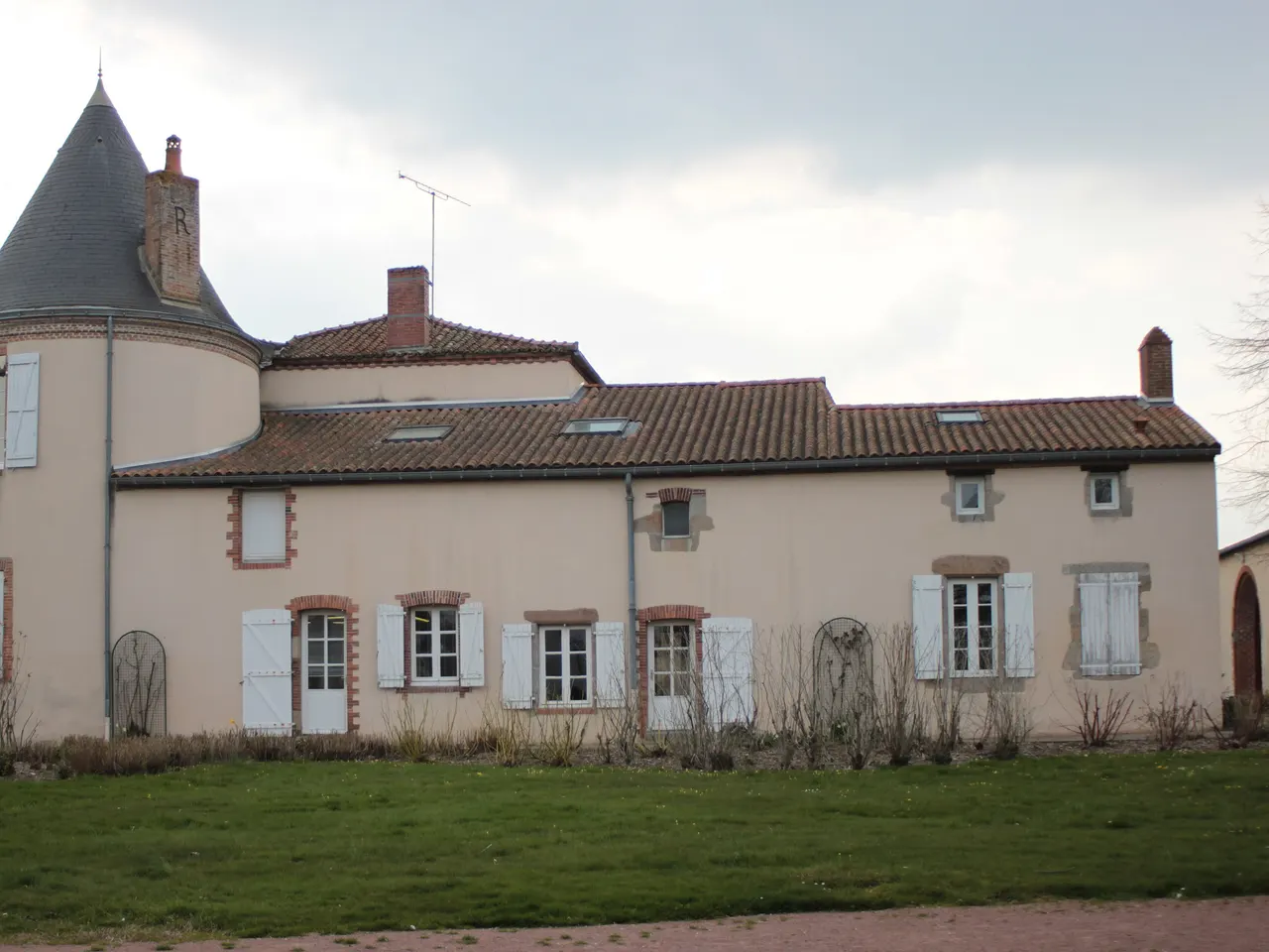 La mairie de Saint-Léger-sous-Cholet, ancien logis du Landreau à tour ronde coiffée d’ardoise, façade rose et volets blancs, sous un ciel gris.