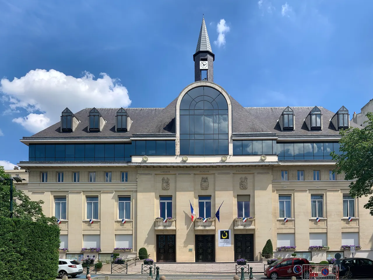 Hôtel de ville de Saint-Mandé, façade claire surmontée d’un clocheton à horloge et d’une grande verrière cintrée, sous un ciel bleu