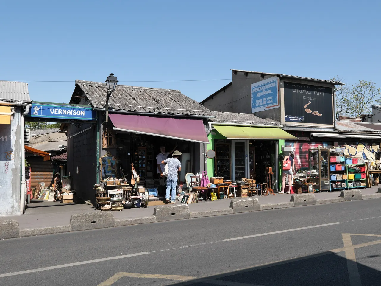L’entrée du marché Vernaison aux Puces de Saint-Ouen, ses échoppes basses et leurs meubles anciens déballés sur le trottoir