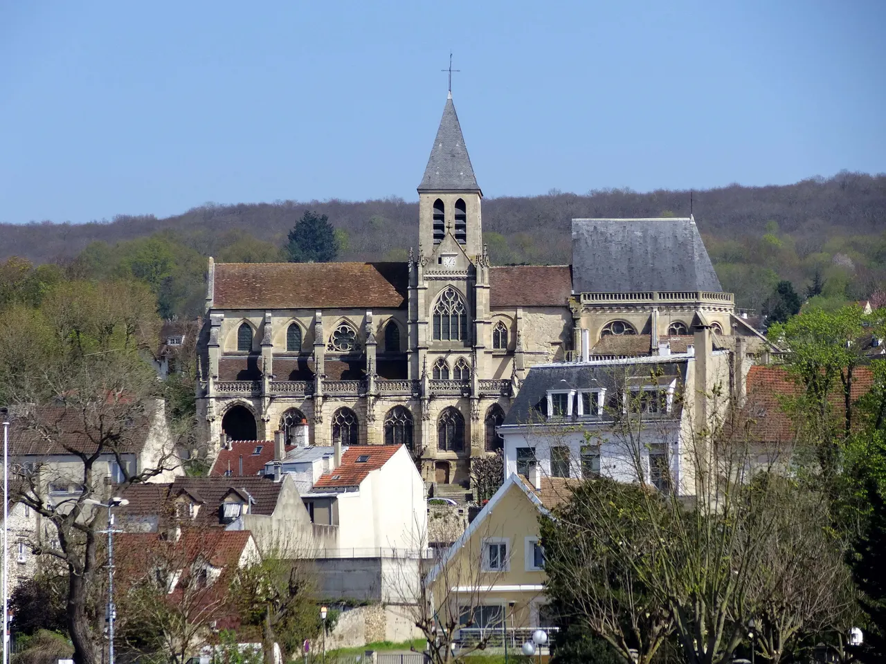 L’église Saint-Martin de Triel-sur-Seine et son clocher d’ardoise dominant les toits du bourg, devant des coteaux boisés.